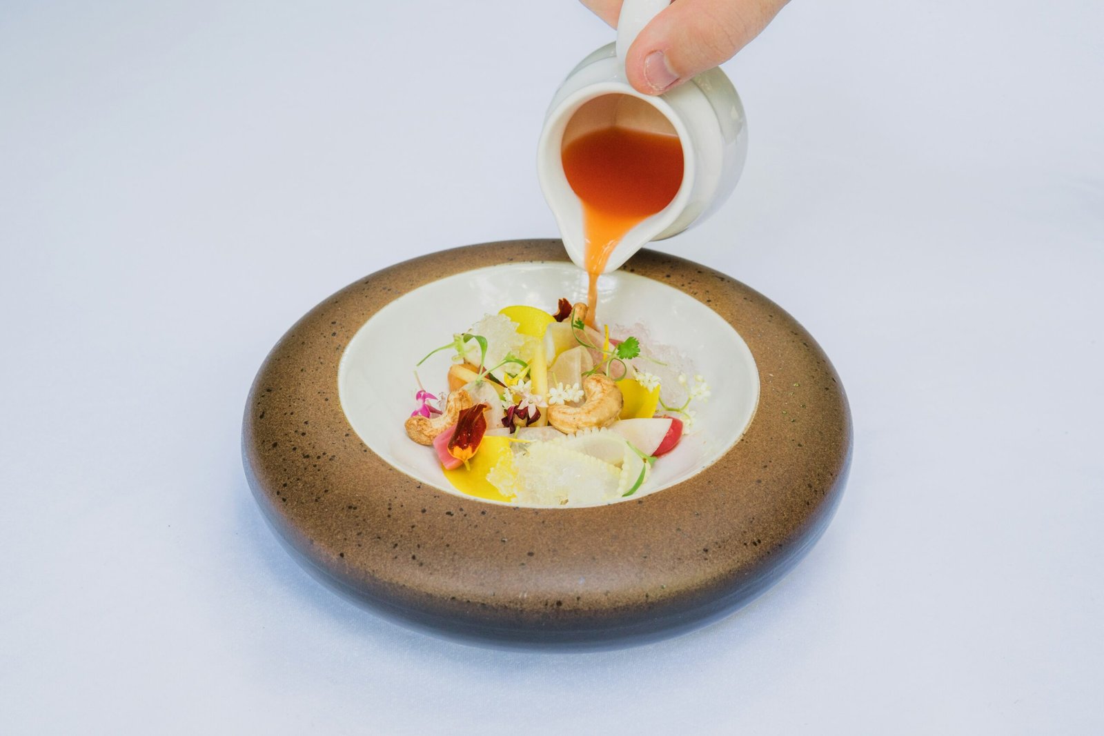 person holding white ceramic bowl with soup